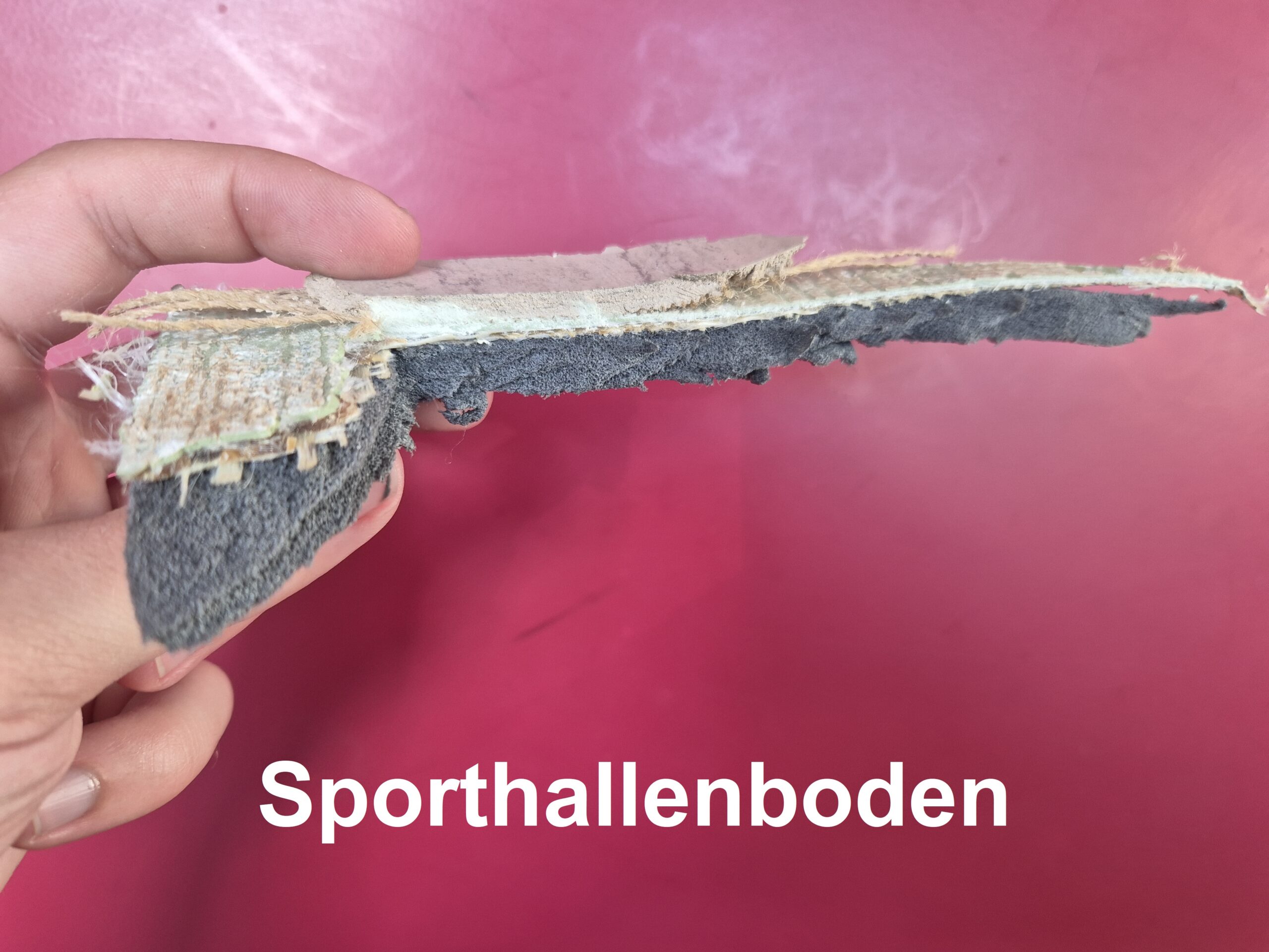 Ein Musterstück eines Sporthallenbodens, der mit dem Bodenstripper entfernt wurde.