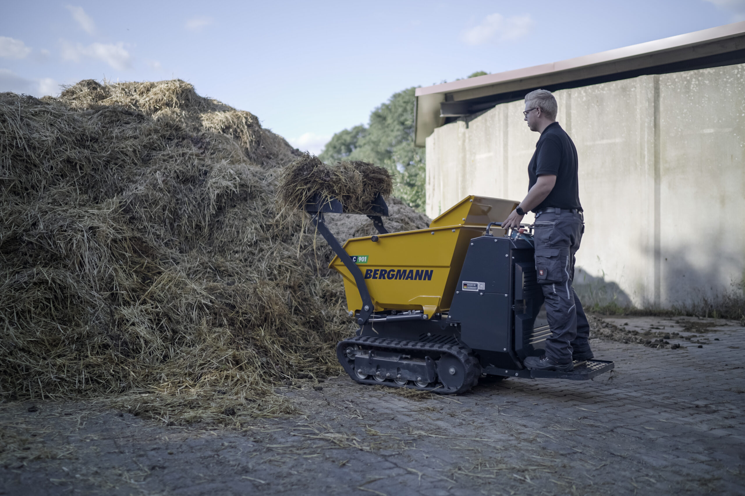 Der Kettendumper lädt sich selbst Heu in die Mulde.