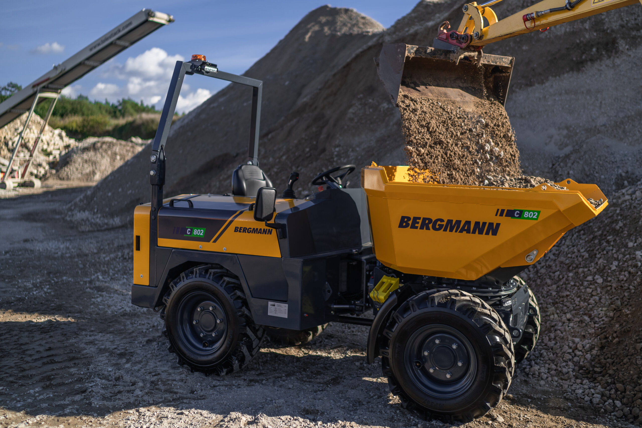 Der Raddumper wird mit einem Bagger mit Kies beladen