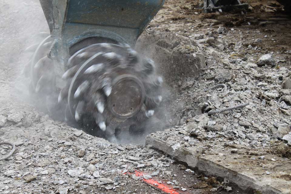 Die Betonfräse an einem Bagger beim Abtragen einers Betonbodens